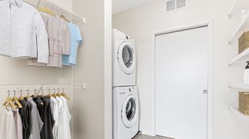 A laundry room with clothes hanging up and a washing machine.